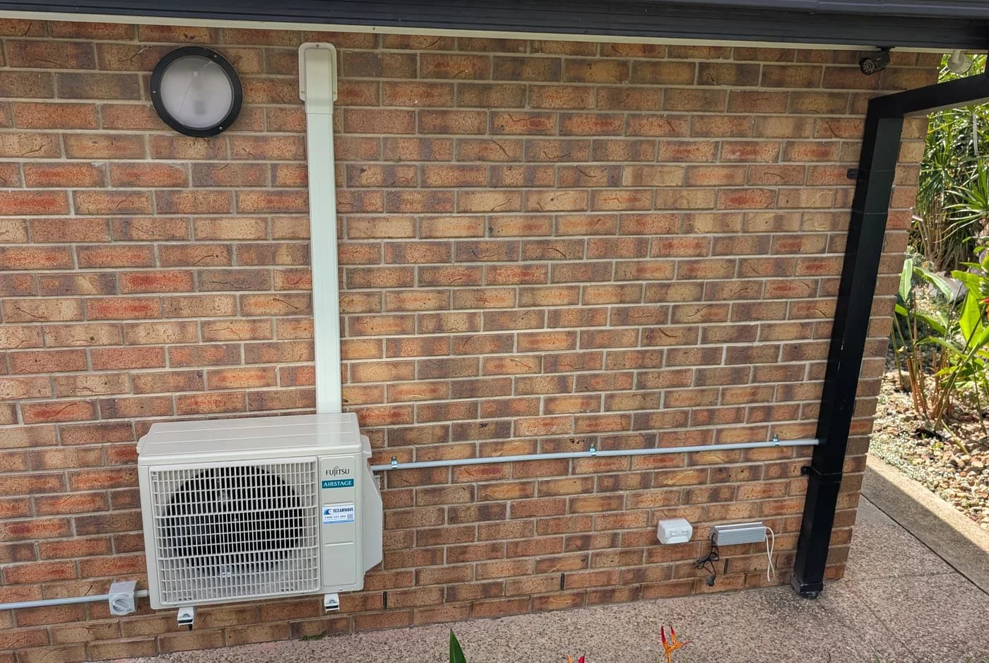 A split-system condenser mounted on the brick wall of a home
