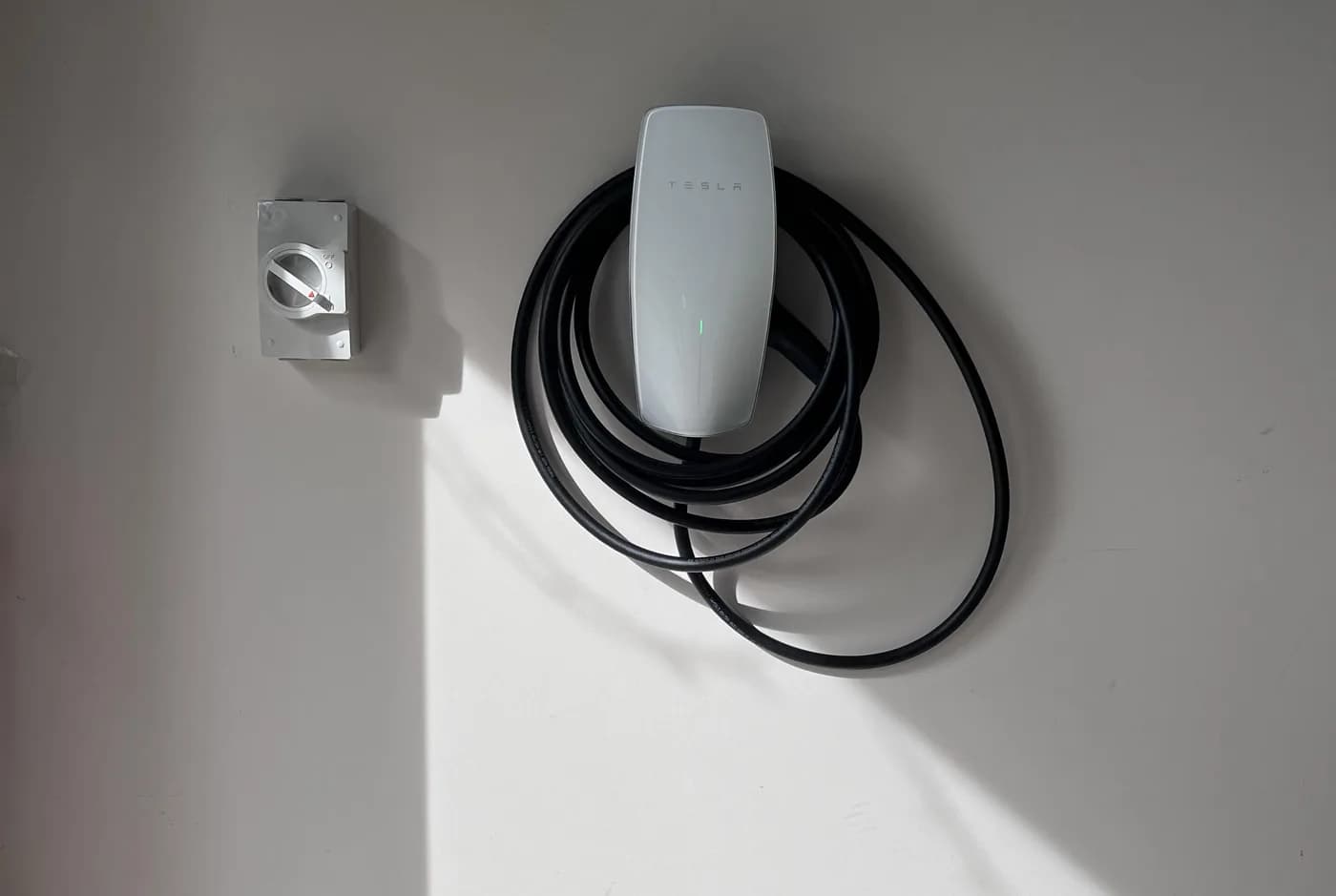 A home EV charger mounted on a wall with the lead coiled