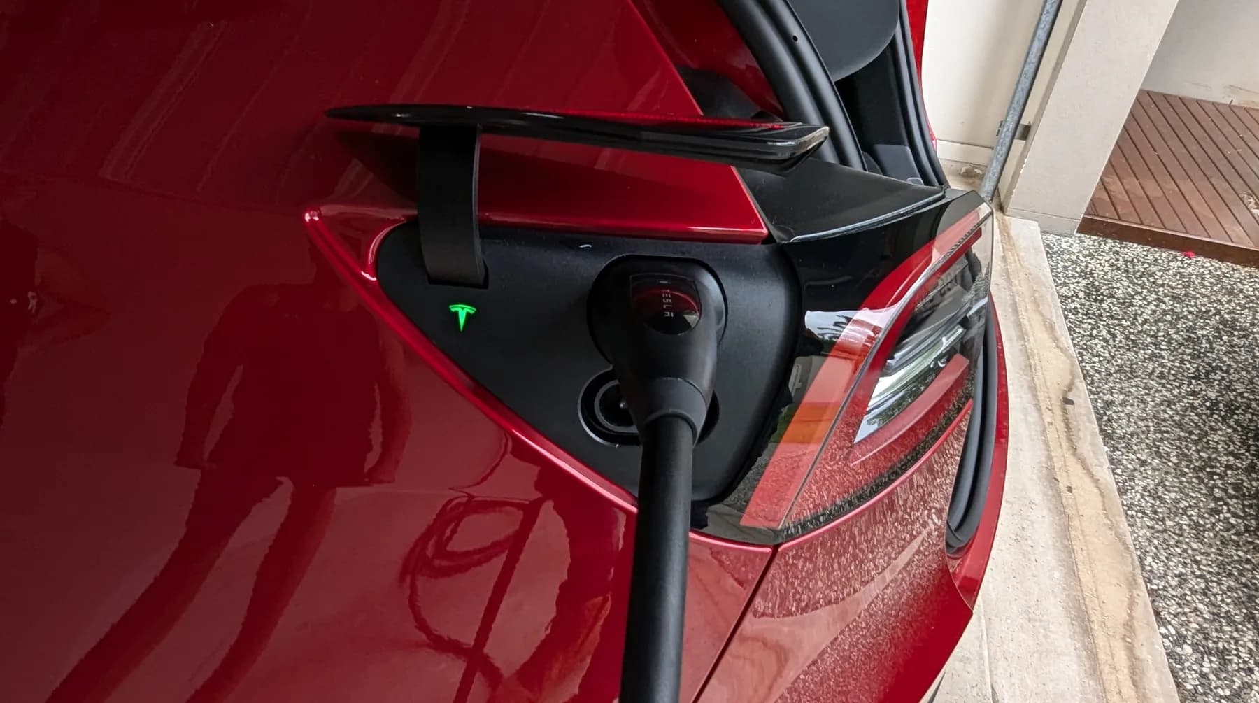 An EV charging lead plugged into the charge port of a car at home