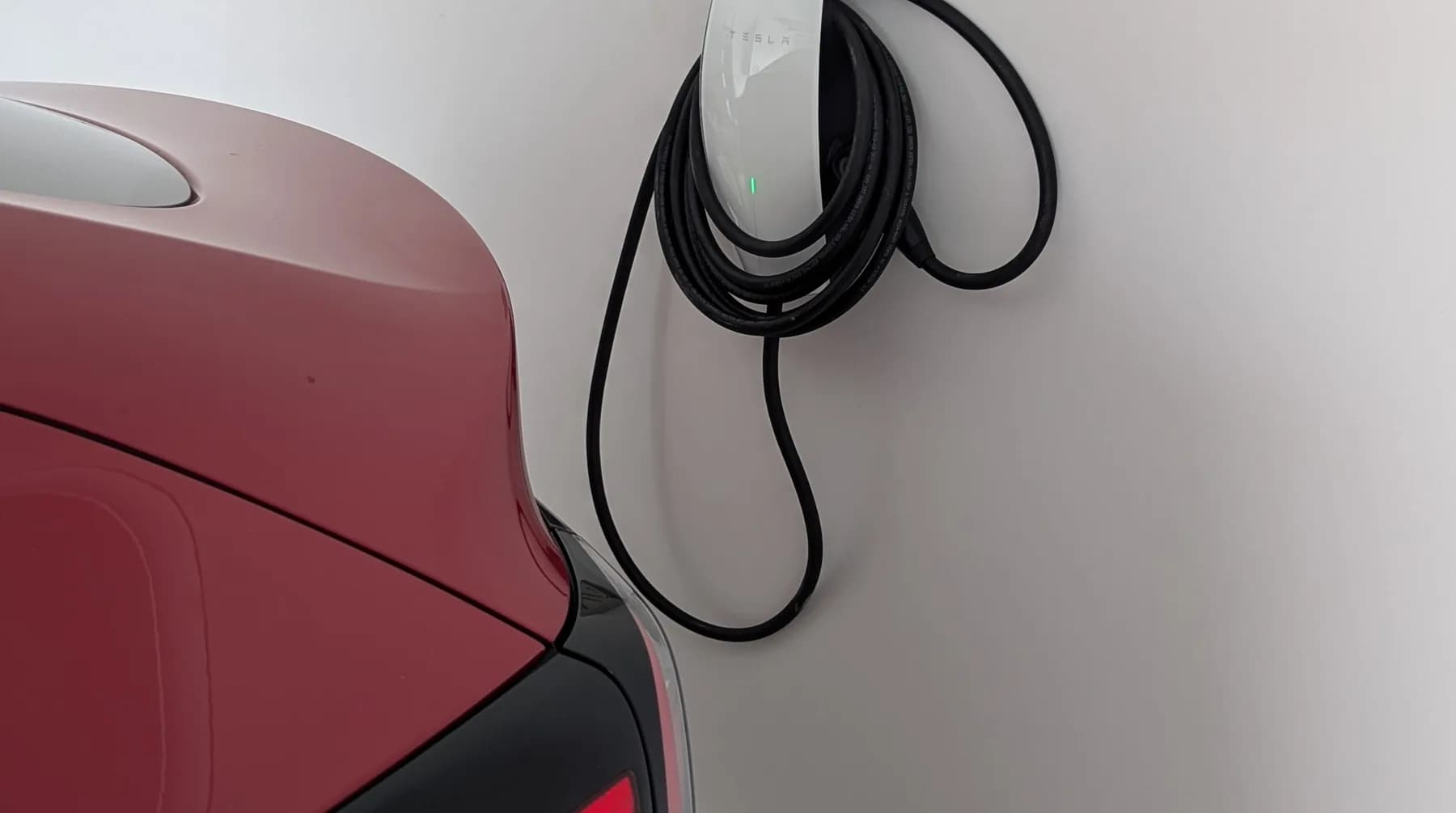 A home EV charger on a garage wall with a car parked alongside