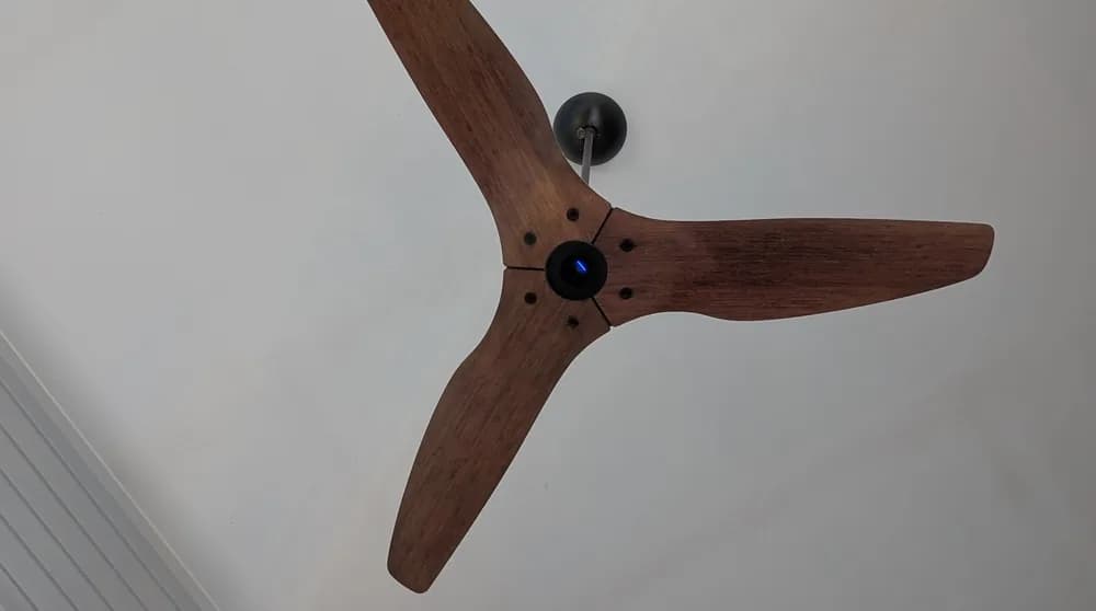 A ceiling fan with timber blades mounted on a white ceiling