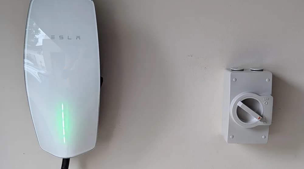 A Tesla wall connector installed beside an isolator on a home wall