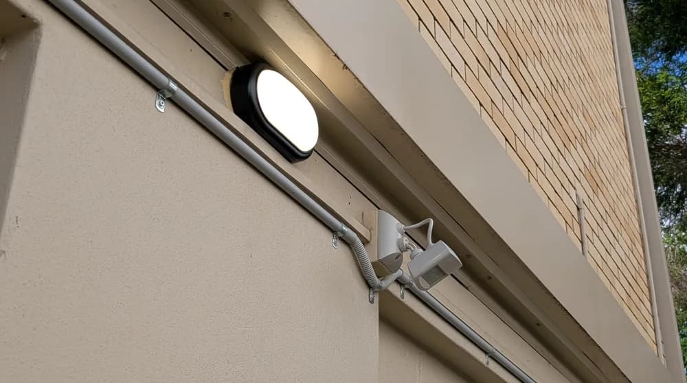 A sensor floodlight mounted under the eave of a brick home