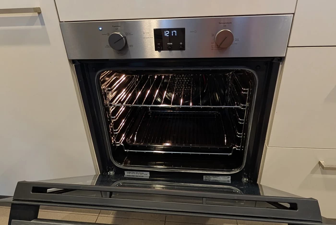 A stainless wall oven with its door open in new cabinetry