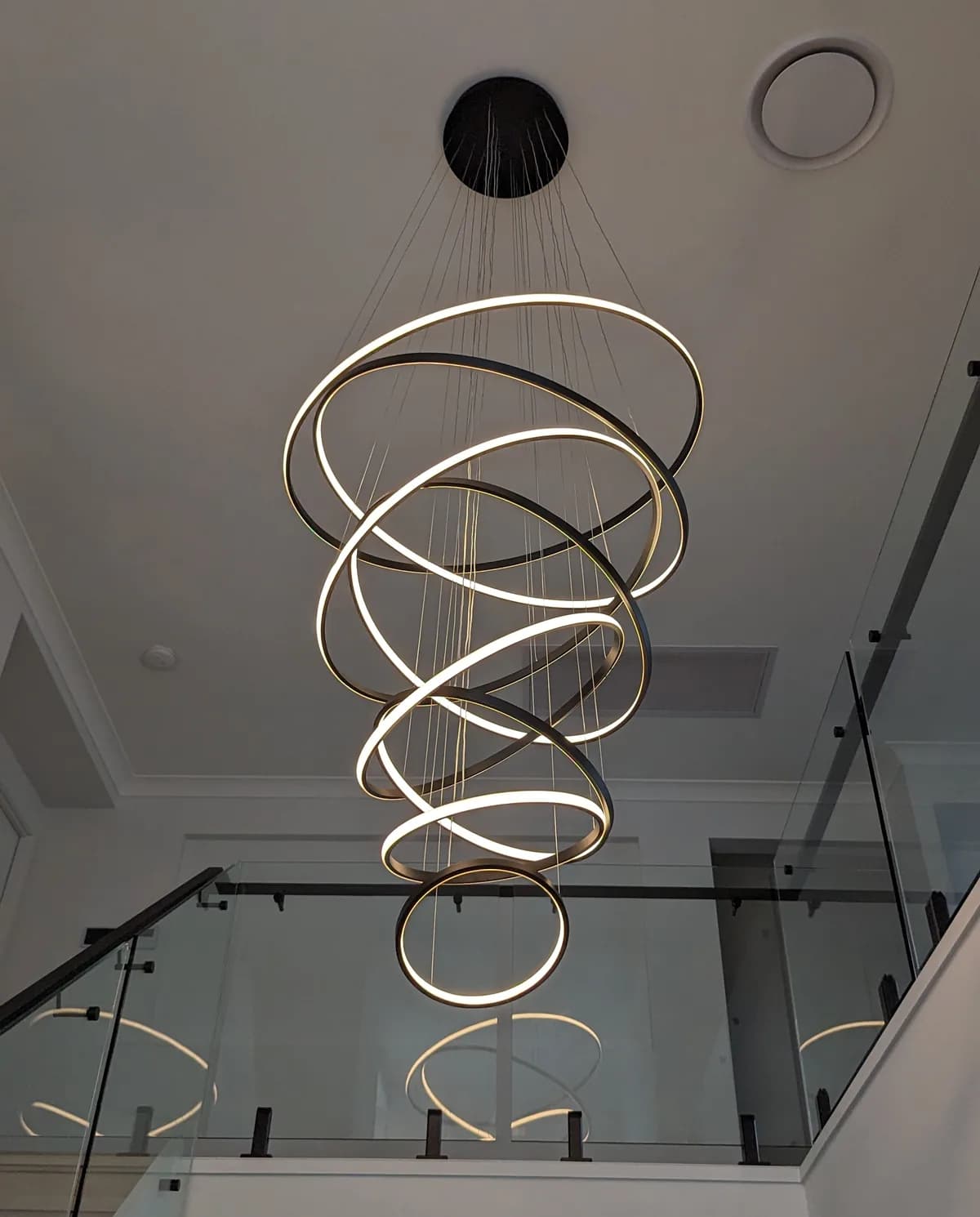 A spiral LED pendant light suspended over a staircase