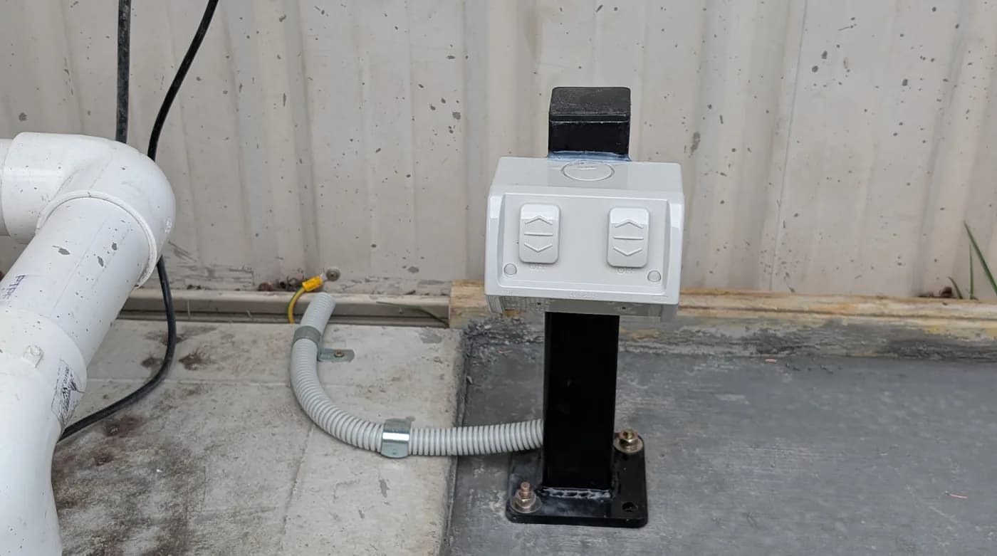 A power outlet mounted on a wall beside conduit and pipework