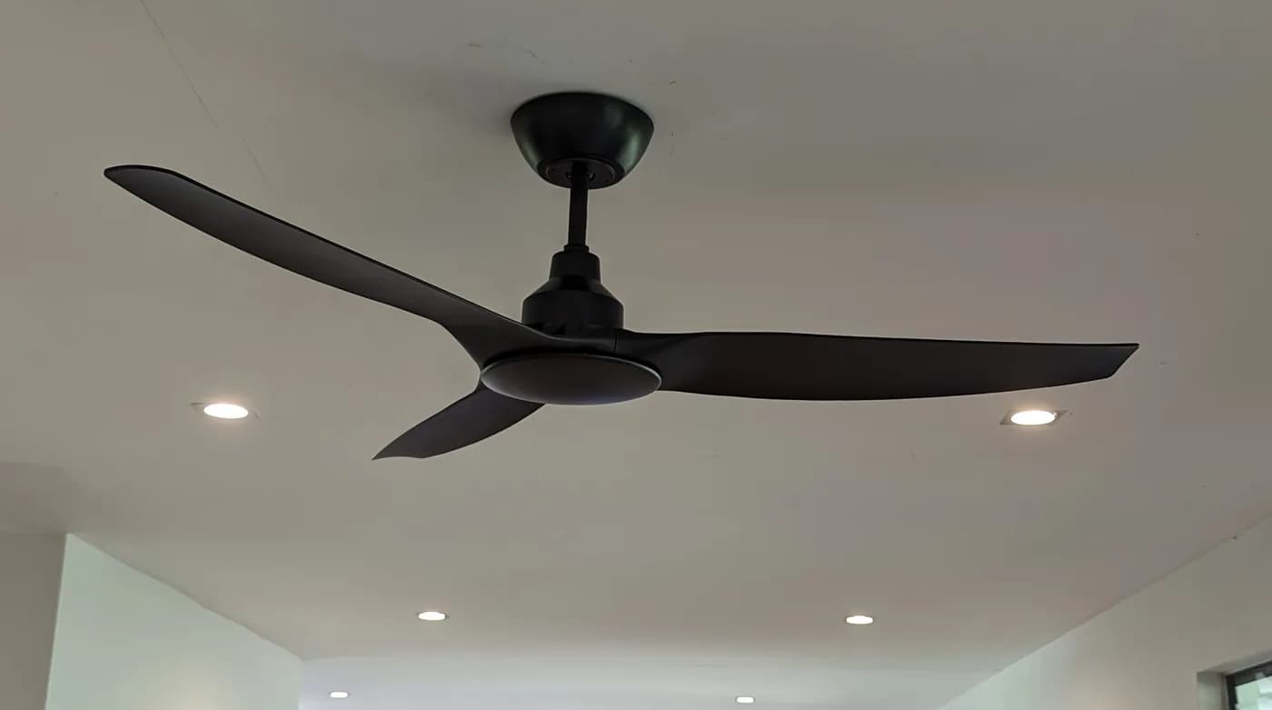 A black ceiling fan installed in a living room with downlights