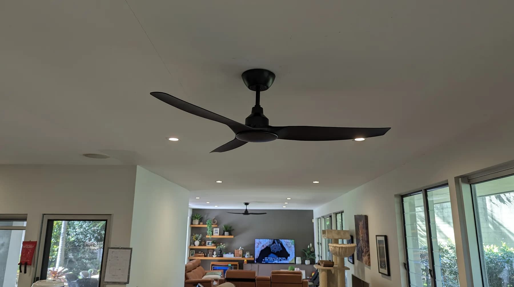 A black three-blade ceiling fan running in an open-plan living room