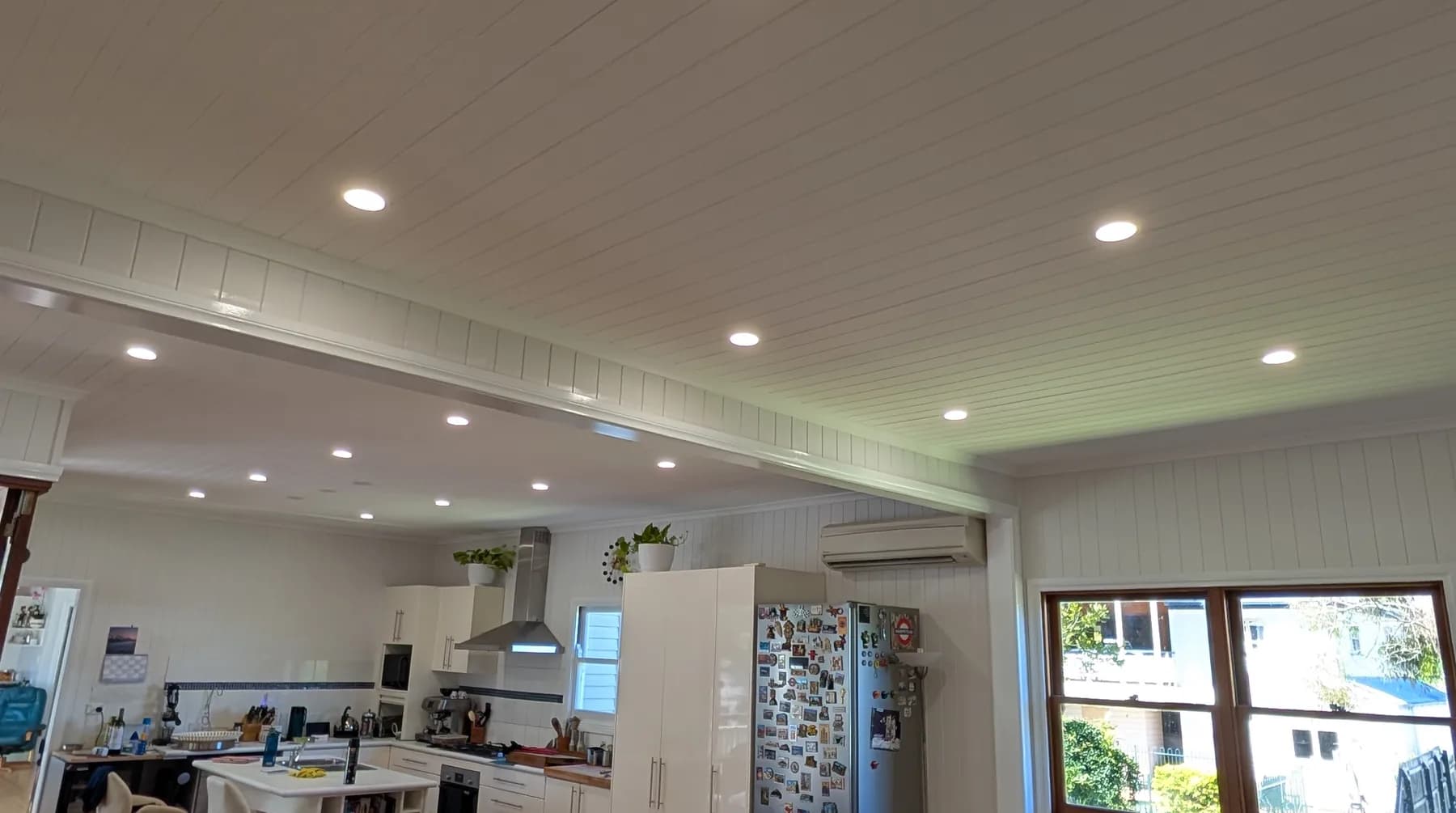 An open-plan living and dining area lit by recessed LED downlights