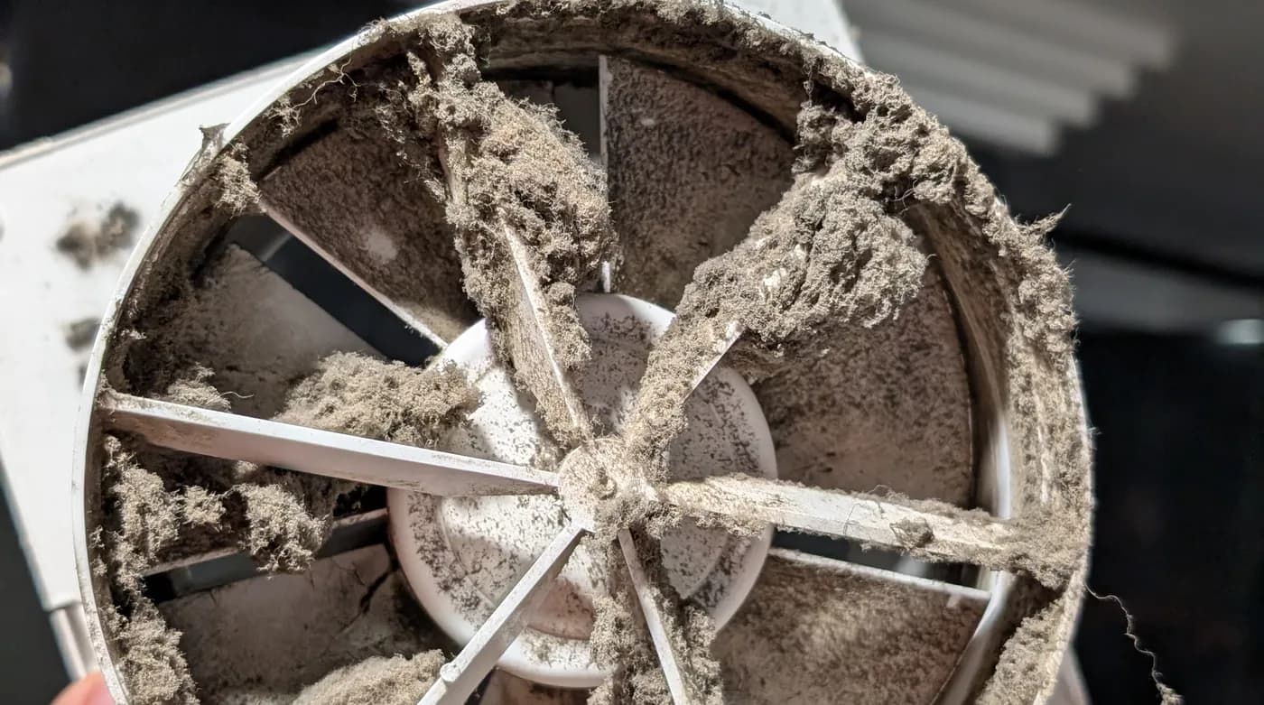 A dust-clogged exhaust fan removed for replacement