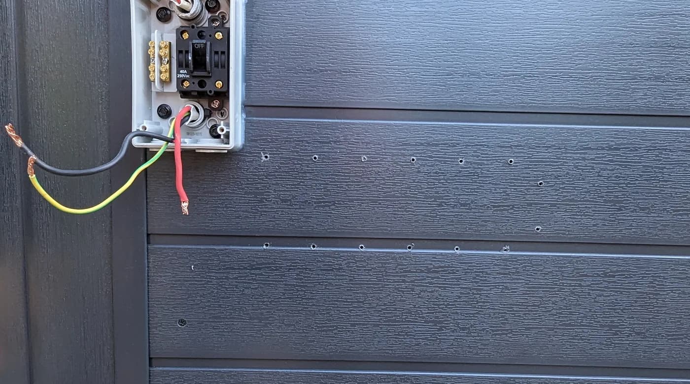 A weatherproof outdoor power point being installed on a cladded wall